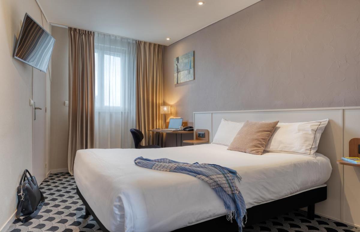 une chambre d'hôtel avec un lit et un bureau dans l'établissement Brit Hotel Les Voyageurs, à Loudéac