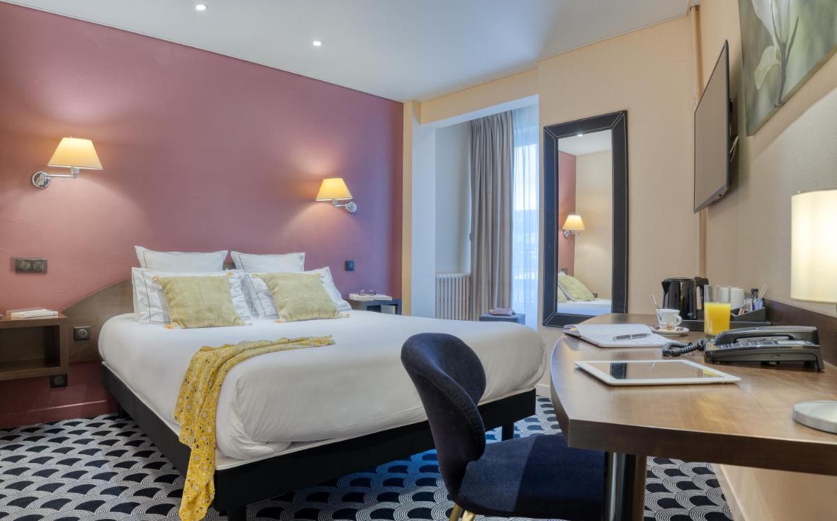 une chambre d'hôtel avec un grand lit et un bureau dans l'établissement Brit Hotel Les Voyageurs, à Loudéac 19 autres photos