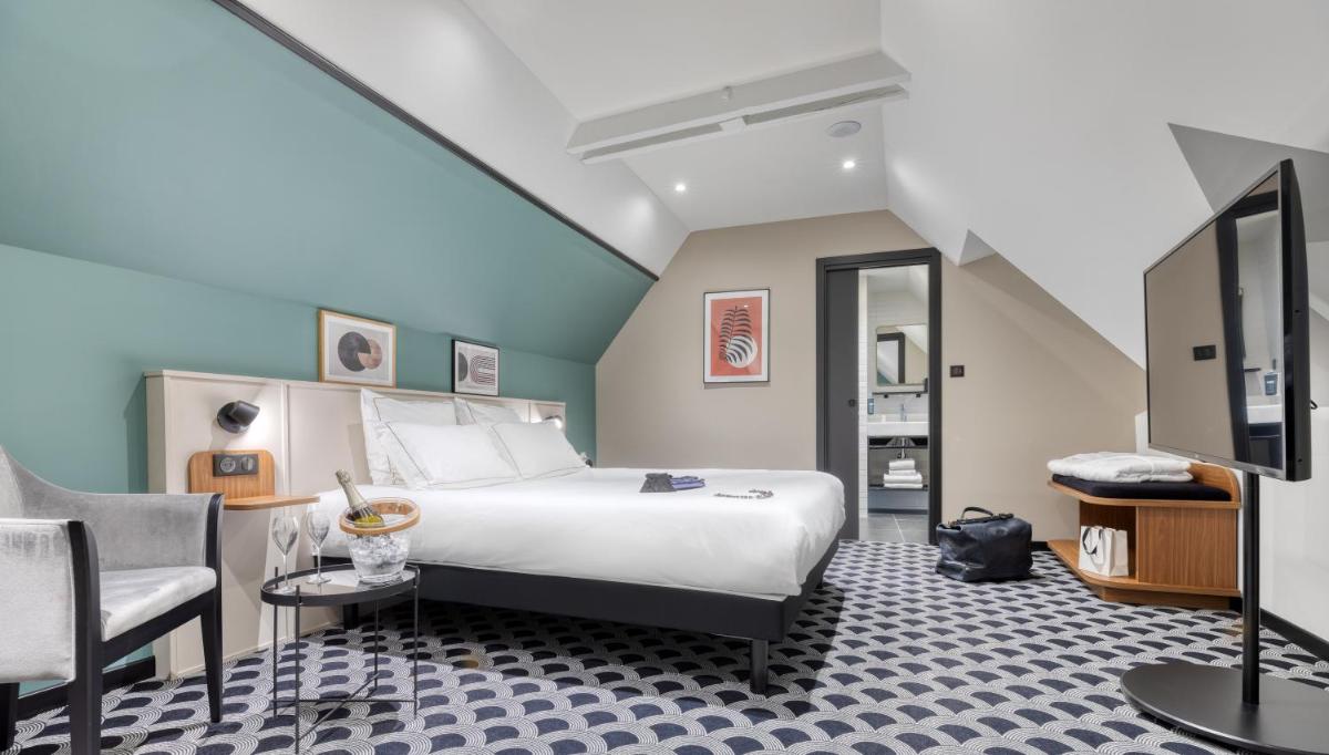 une chambre d'hôtel avec un lit et une chaise dans l'établissement Brit Hotel Les Voyageurs, à Loudéac