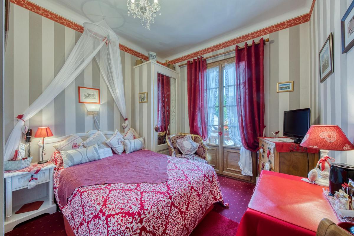 - une chambre avec un lit rose et une télévision dans l'établissement Les Cygnes, à Évian-les-Bains