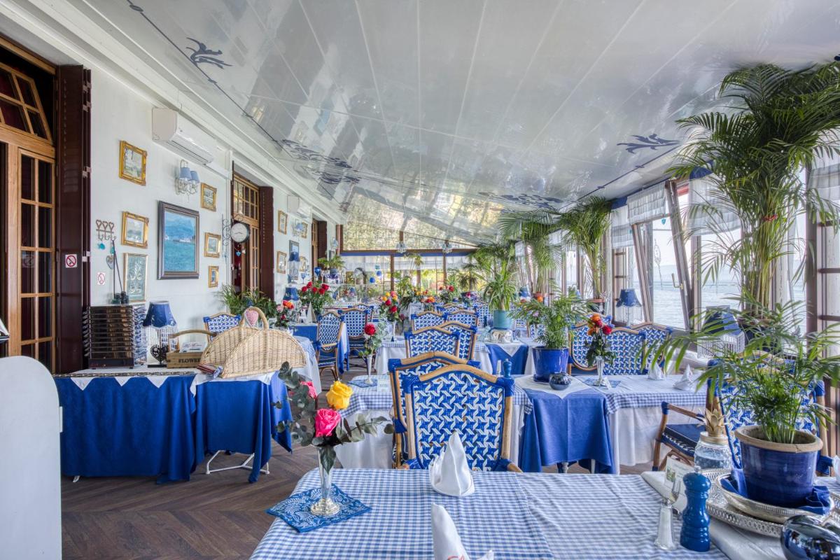 un restaurant avec des tables bleues, des chaises et des plantes dans l'établissement Les Cygnes, à Évian-les-Bains