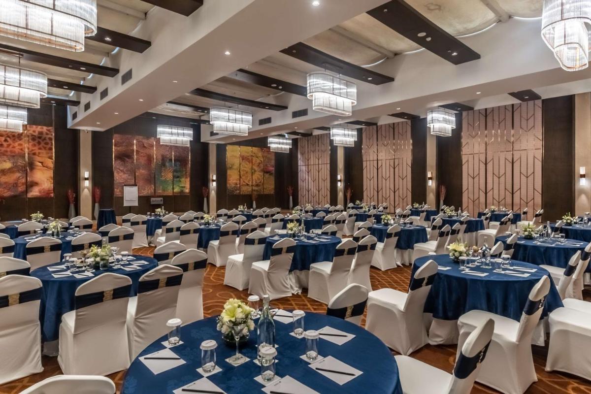a large banquet hall with blue tables and white chairs at Radisson Blu Hotel, Greater Noida in Greater Noida