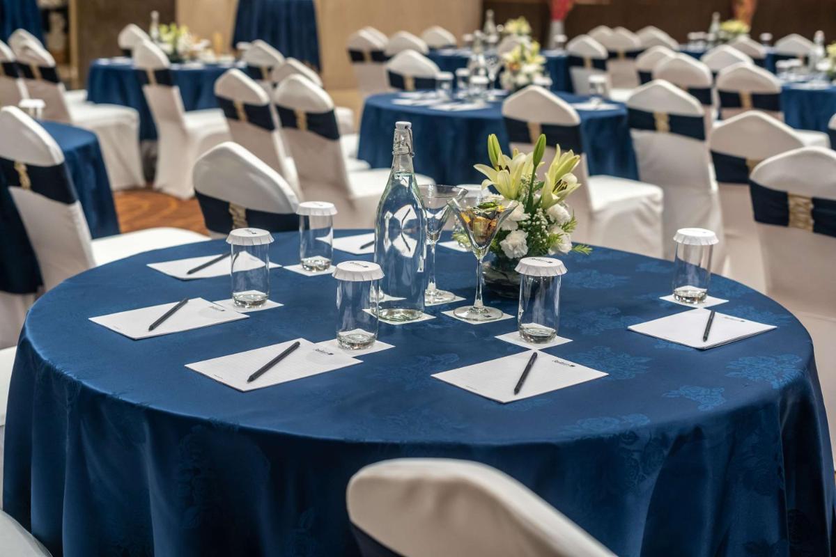 a blue table with napkins and wine glasses on it at Radisson Blu Hotel, Greater Noida in Greater Noida