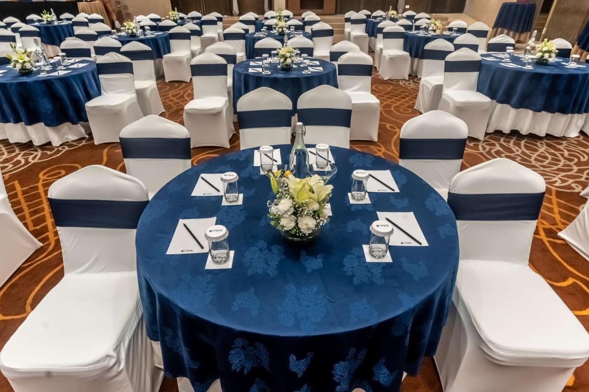 a room with a blue table and white chairs at Radisson Blu Hotel, Greater Noida in Greater Noida