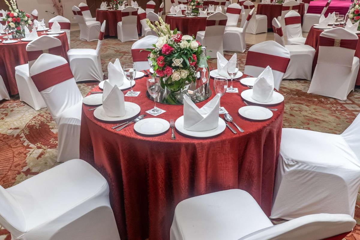 a table with white chairs and a red table cloth at Radisson Blu Hotel, Greater Noida in Greater Noida