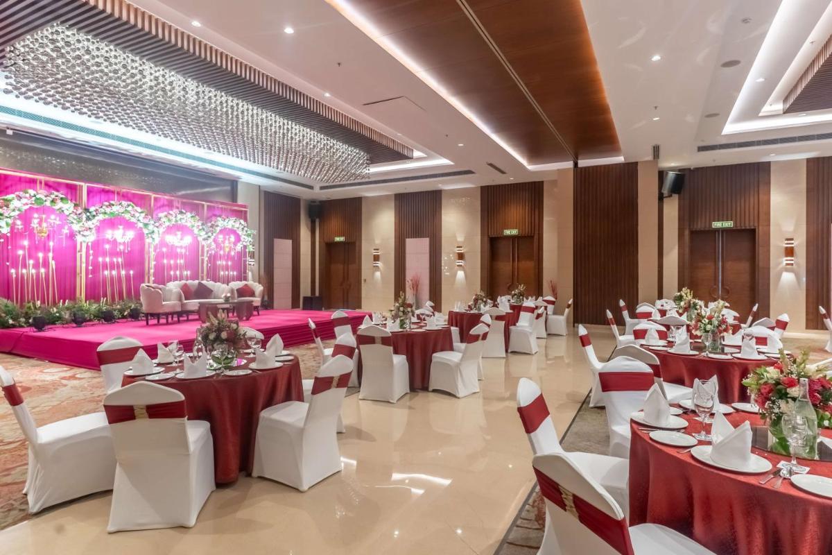 a banquet hall with red and white tables and chairs at Radisson Blu Hotel, Greater Noida in Greater Noida