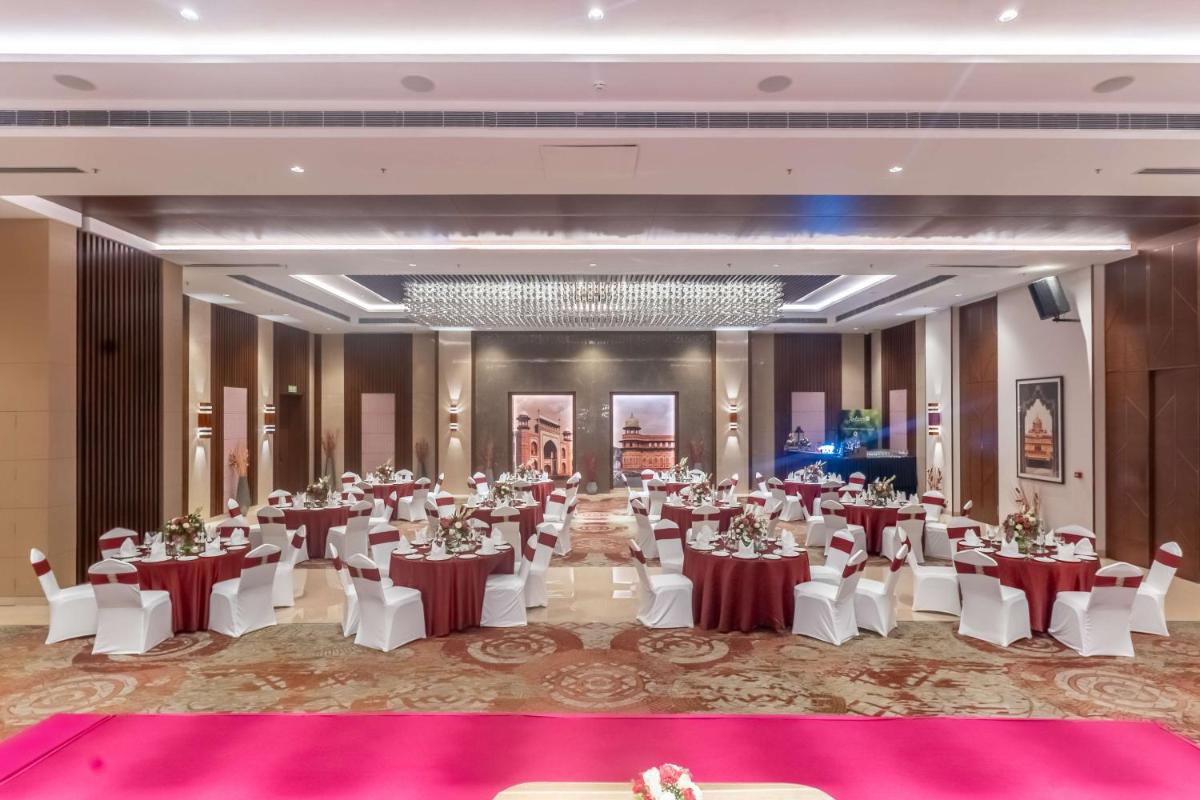 a banquet hall with tables and chairs and a chandelier at Radisson Blu Hotel, Greater Noida in Greater Noida
