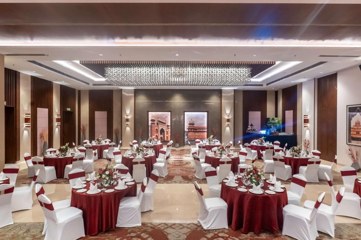 a banquet hall with tables and chairs and a chandelier at Radisson Blu Hotel, Greater Noida in Greater Noida +155 photos