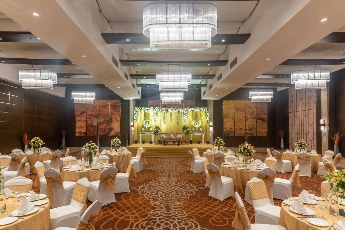 a banquet hall with tables and chairs and a stage at Radisson Blu Hotel, Greater Noida in Greater Noida