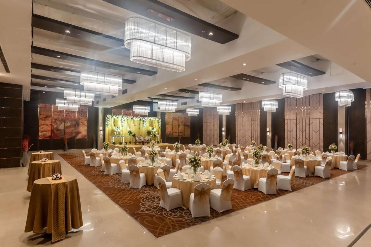 a banquet hall with white tables and white chairs at Radisson Blu Hotel, Greater Noida in Greater Noida