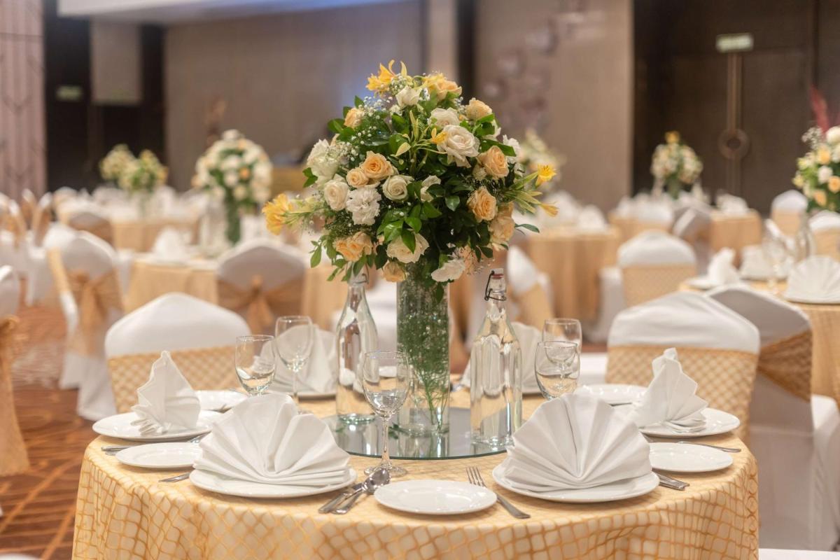 a table with a vase of flowers on it at Radisson Blu Hotel, Greater Noida in Greater Noida