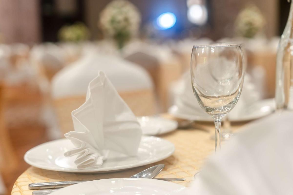 a table with white plates and a glass of wine at Radisson Blu Hotel, Greater Noida in Greater Noida