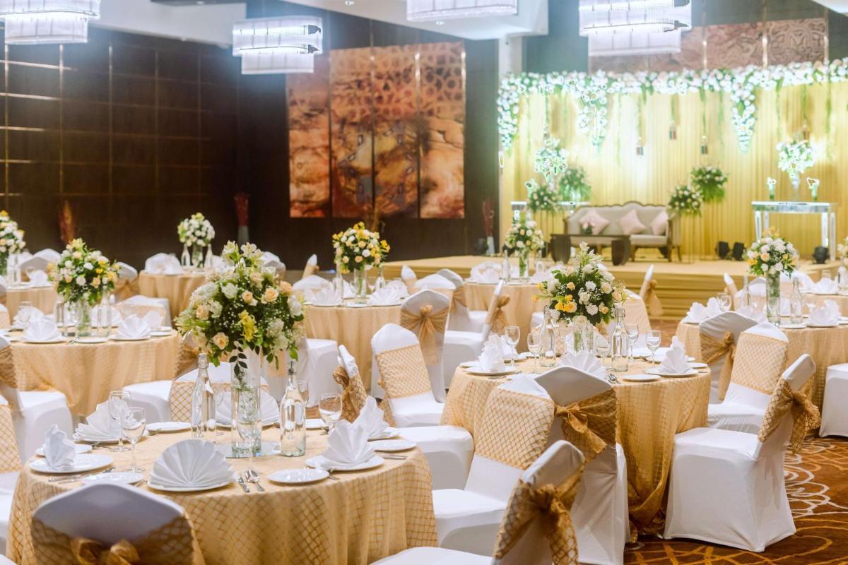 a banquet hall with white tables and white chairs at Radisson Blu Hotel, Greater Noida in Greater Noida