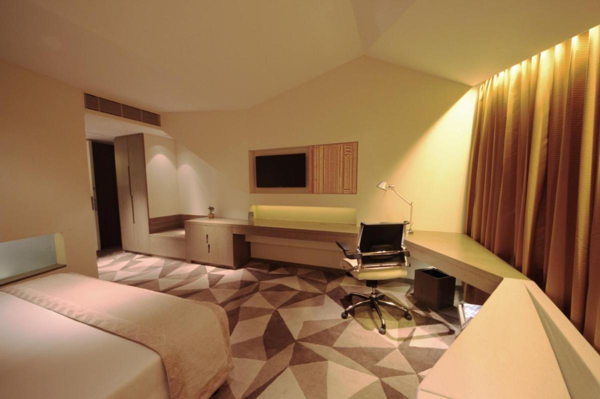 a hotel room with a bed and a desk at Vivanta New Delhi, Dwarka in New Delhi a hotel room with a bed and a desk at Vivanta New Delhi, Dwarka in New Delhi