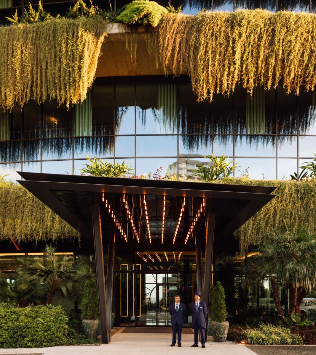 Dois homens de fato em frente a um edifício com videiras. em The Reserve - within Savoy Palace - The Leading Hotels of the World no Funchal