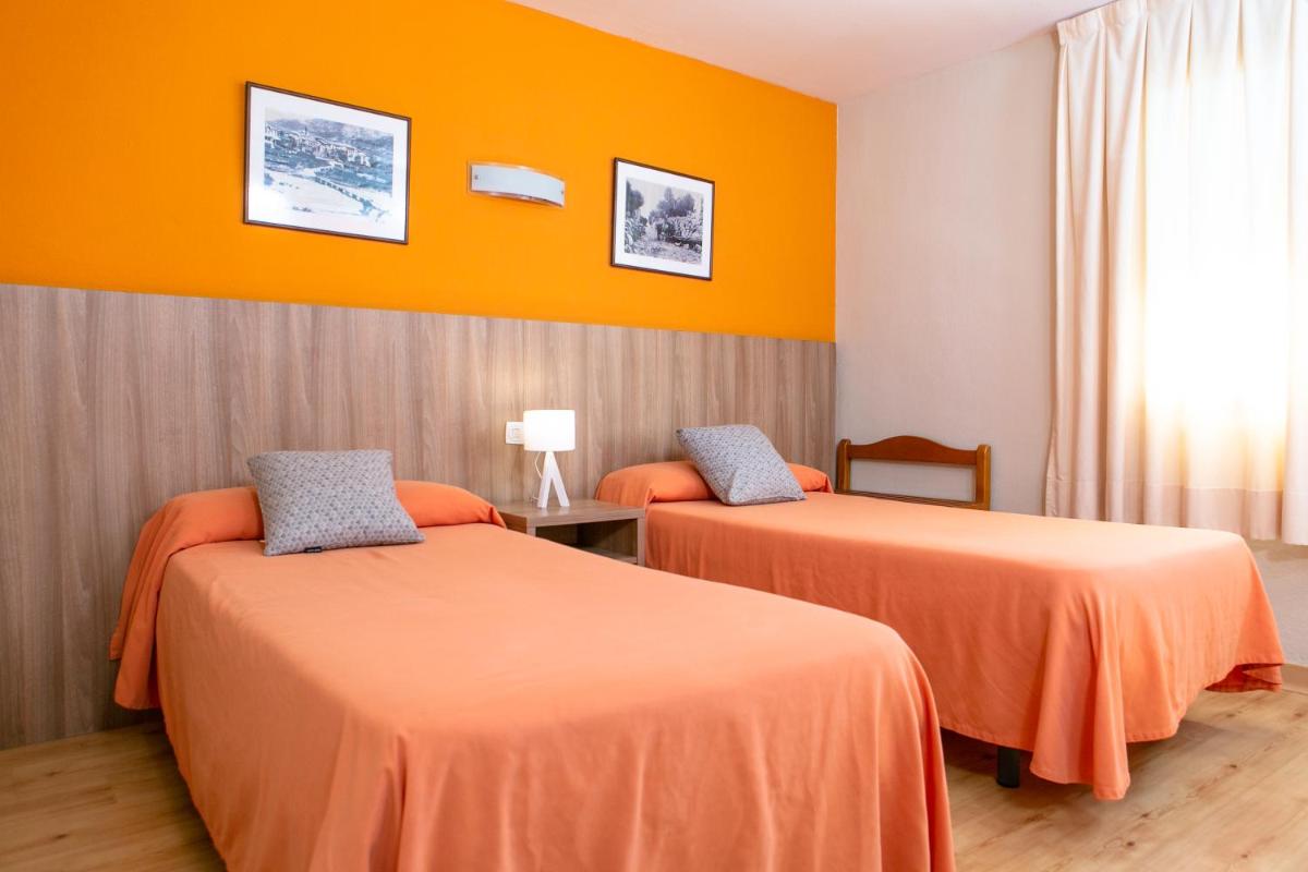 Dos camas en una habitación con paredes naranjas. en Hotel Snö Condes del Pallars, en Rialp 36 fotos más