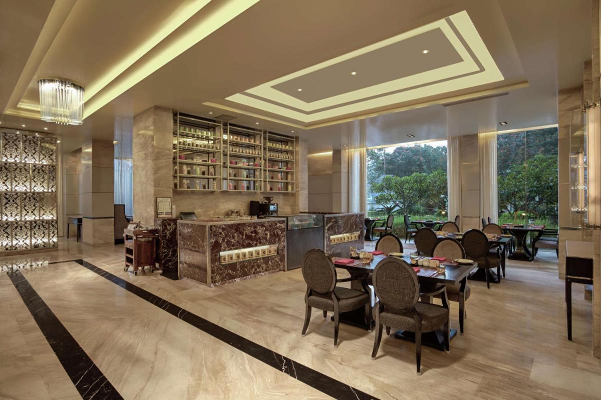 a dining room with tables and chairs in a building at DoubleTree Suites by Hilton Bengaluru Outer Ring Road in Bengaluru