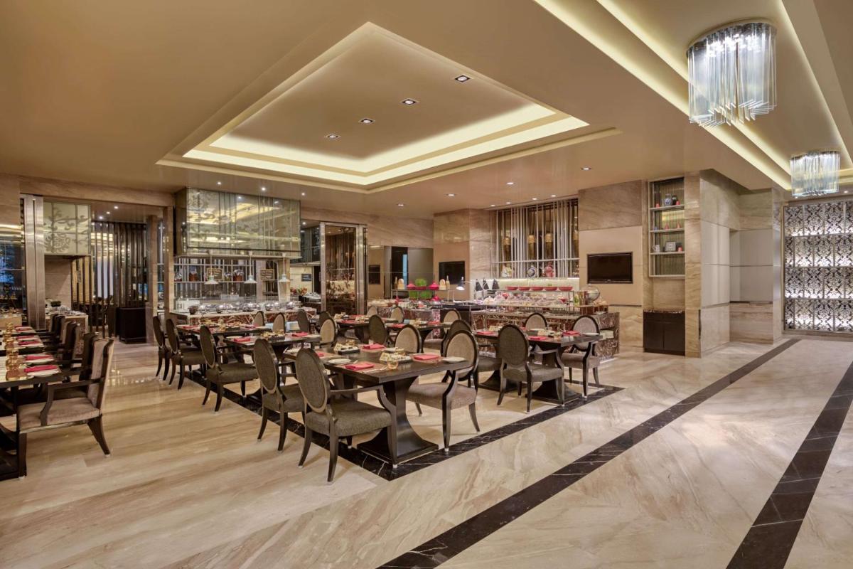 a restaurant with tables and chairs in a room at DoubleTree Suites by Hilton Bengaluru Outer Ring Road in Bengaluru