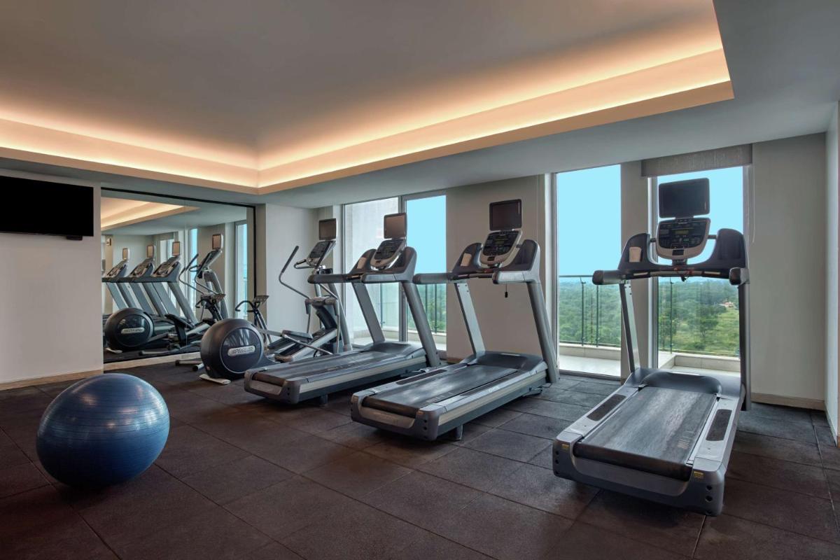 a gym with several tread machines and a large window at DoubleTree Suites by Hilton Bengaluru Outer Ring Road in Bengaluru