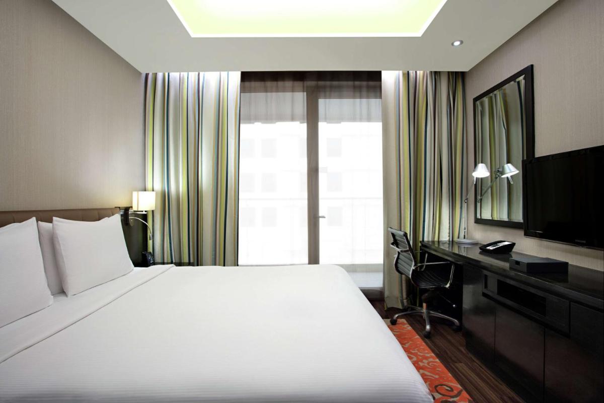 a hotel room with a large bed and a television at DoubleTree Suites by Hilton Bengaluru Outer Ring Road in Bengaluru