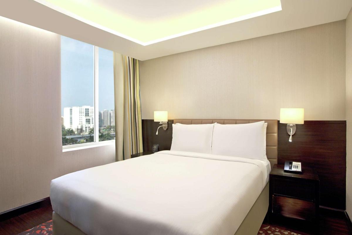 a large white bed in a hotel room with a window at DoubleTree Suites by Hilton Bengaluru Outer Ring Road in Bengaluru