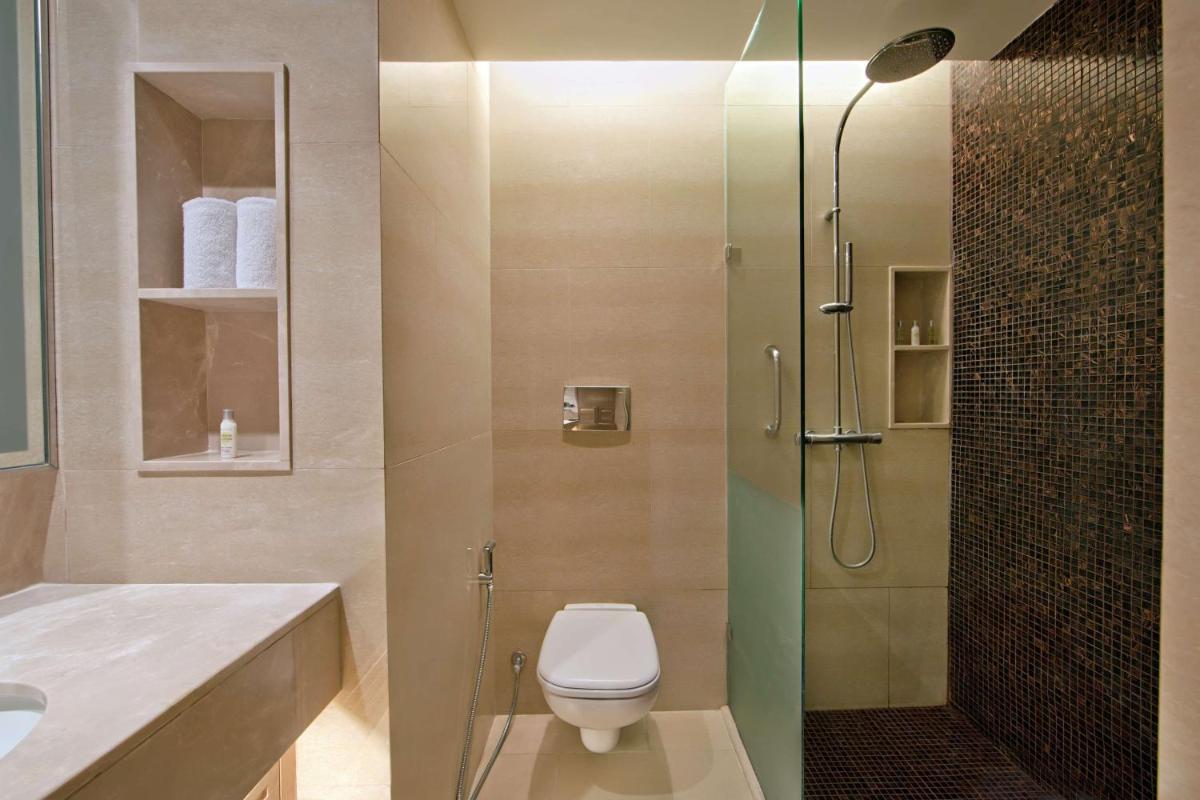 a bathroom with a toilet and a glass shower at DoubleTree Suites by Hilton Bengaluru Outer Ring Road in Bengaluru