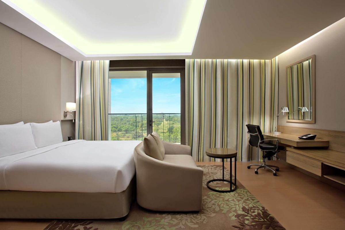 a hotel room with a bed and a desk and a window at DoubleTree Suites by Hilton Bengaluru Outer Ring Road in Bengaluru
