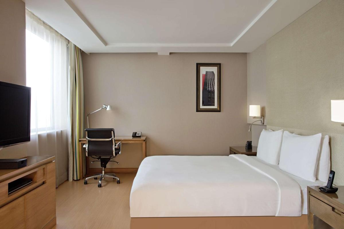 a hotel room with a large bed and a television at DoubleTree Suites by Hilton Bengaluru Outer Ring Road in Bengaluru