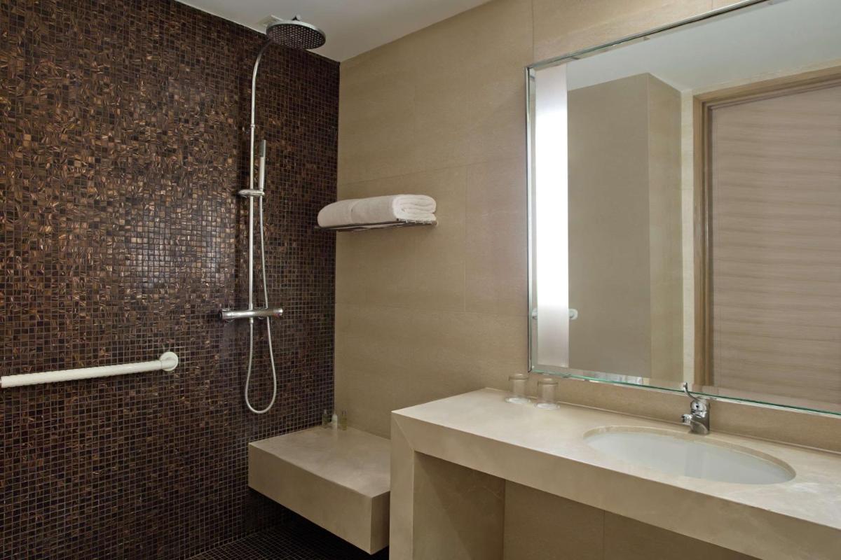 a bathroom with a sink and a shower with a mirror at DoubleTree Suites by Hilton Bengaluru Outer Ring Road in Bengaluru