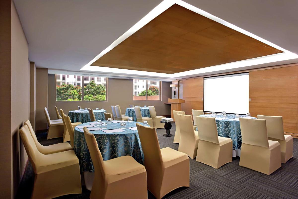 a conference room with tables and chairs and a screen at DoubleTree Suites by Hilton Bengaluru Outer Ring Road in Bengaluru