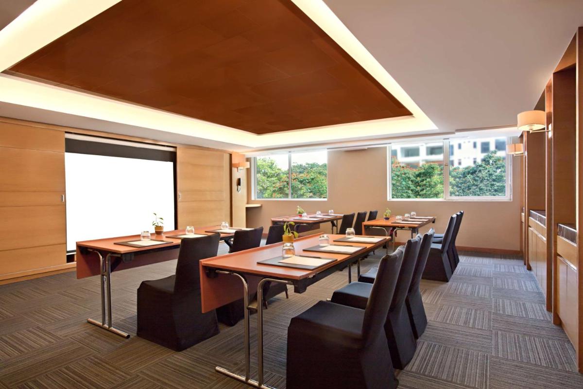 a restaurant with wooden tables and chairs and a large window at DoubleTree Suites by Hilton Bengaluru Outer Ring Road in Bengaluru