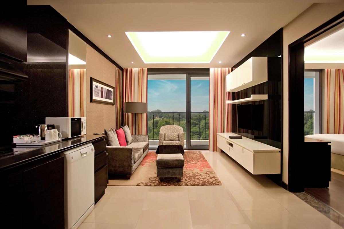 a living room with a television and a couch and a chair at DoubleTree Suites by Hilton Bengaluru Outer Ring Road in Bengaluru