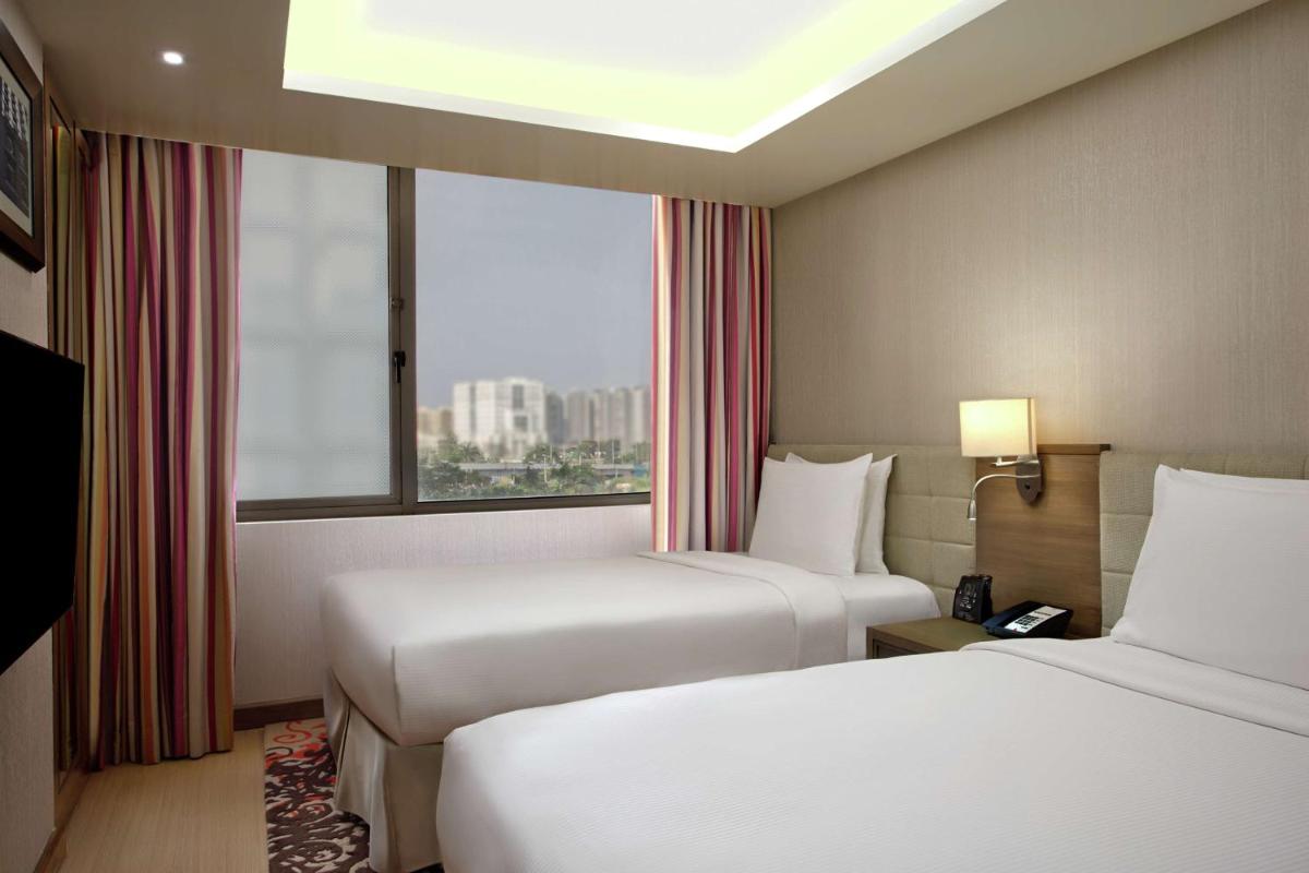 a hotel room with two beds and a window at DoubleTree Suites by Hilton Bengaluru Outer Ring Road in Bengaluru