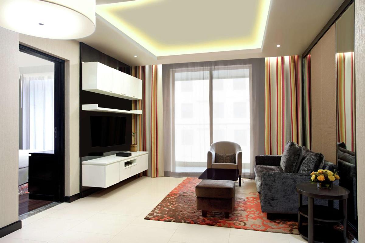 a living room with a couch and a tv at DoubleTree Suites by Hilton Bengaluru Outer Ring Road in Bengaluru