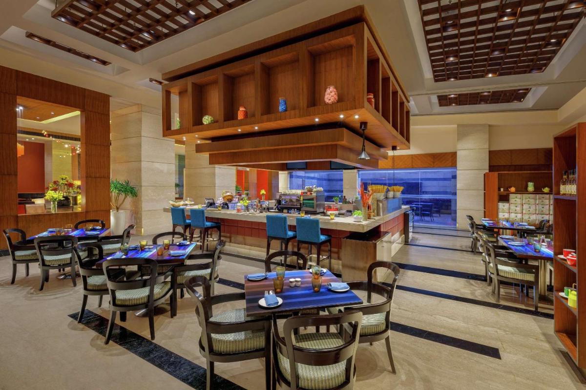 a restaurant with tables and chairs and a bar at DoubleTree by Hilton Gurgaon New Delhi NCR in Gurgaon a restaurant with tables and chairs and a bar at DoubleTree by Hilton Gurgaon New Delhi NCR in Gurgaon