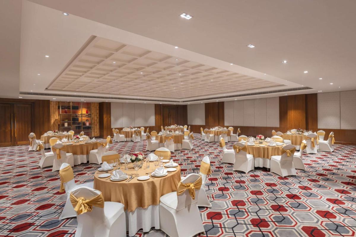 a banquet hall with tables and white chairs at DoubleTree by Hilton Gurgaon New Delhi NCR in Gurgaon