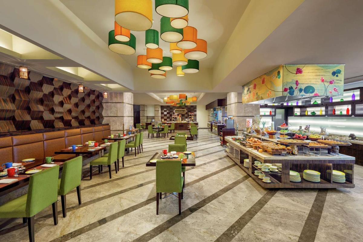 a restaurant with tables and chairs and a buffet at DoubleTree by Hilton Gurgaon New Delhi NCR in Gurgaon