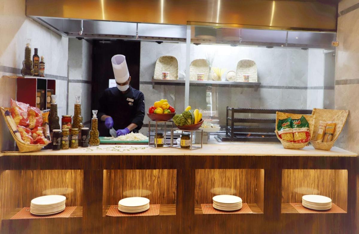 a chef preparing food in a restaurant kitchen at DoubleTree by Hilton Gurgaon New Delhi NCR in Gurgaon