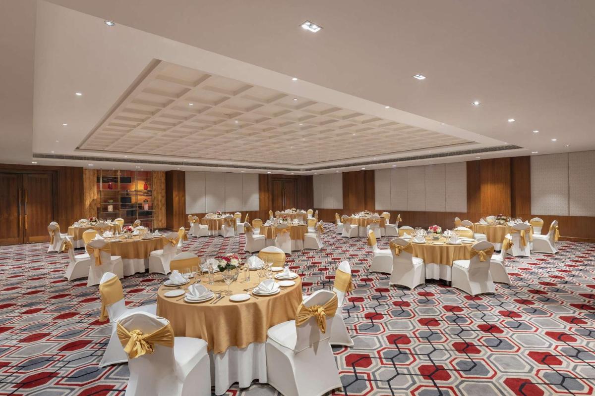 a banquet hall filled with tables and chairs with bows at DoubleTree by Hilton Gurgaon New Delhi NCR in Gurgaon