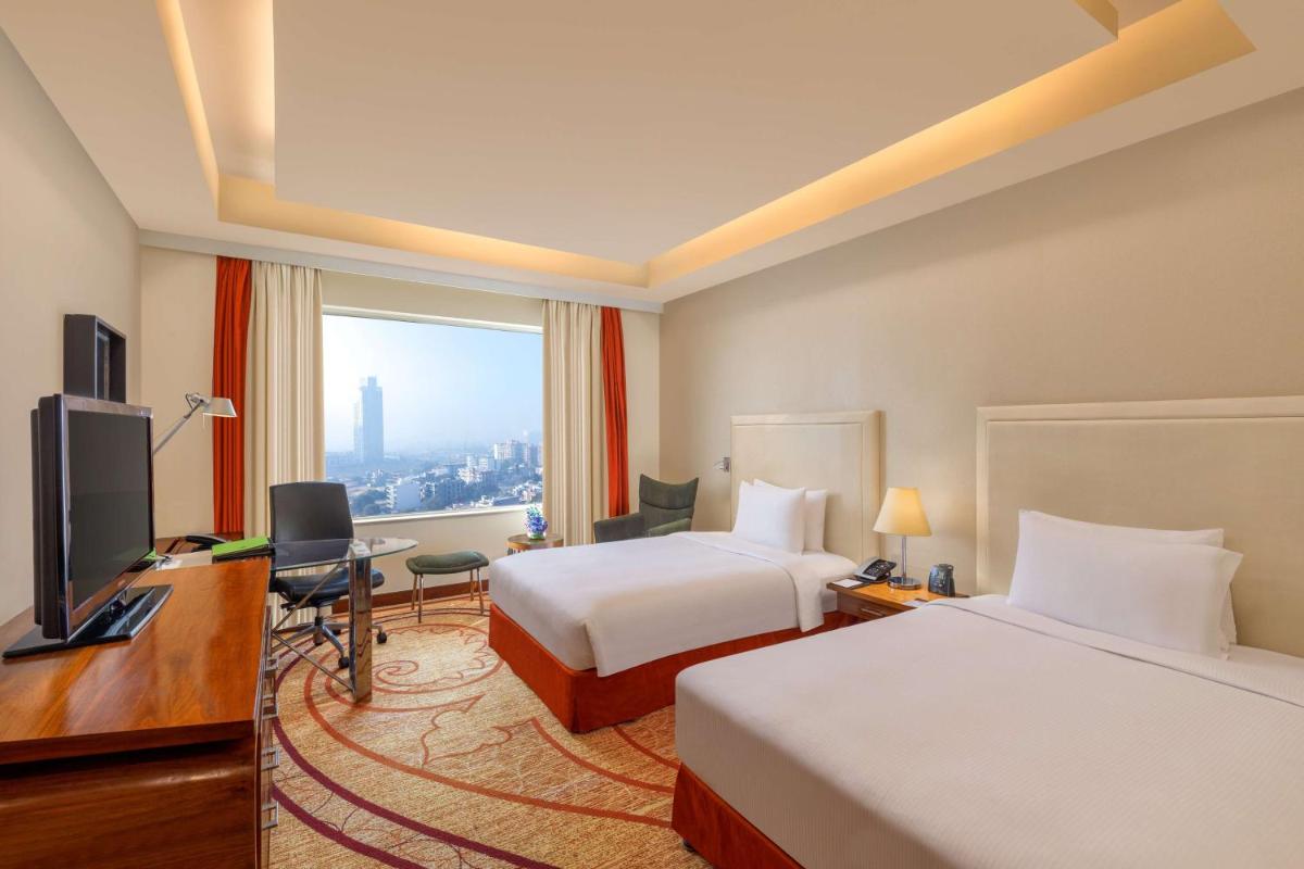 a hotel room with two beds and a desk and a television at DoubleTree by Hilton Gurgaon New Delhi NCR in Gurgaon