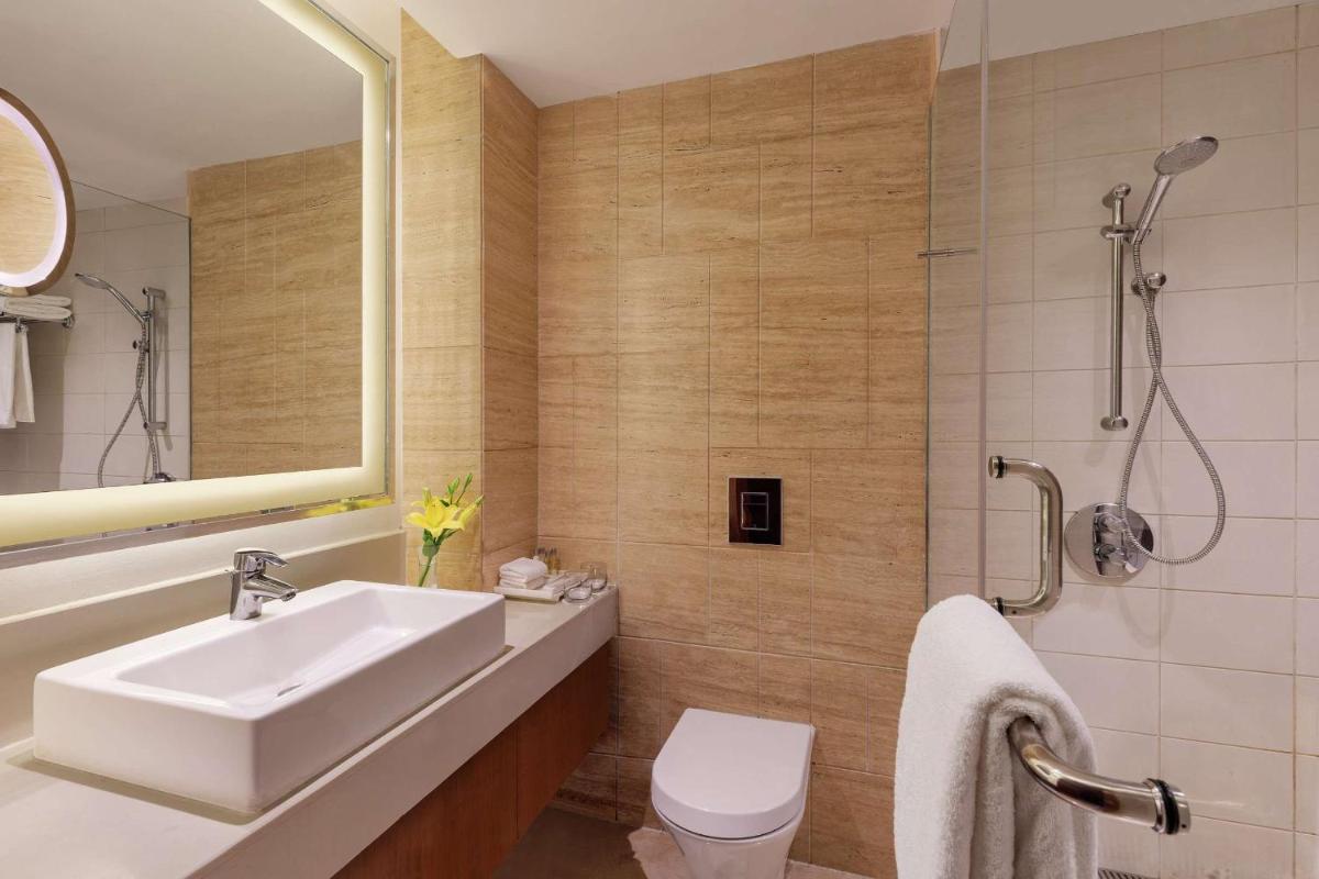 a bathroom with a sink and a toilet and a mirror at DoubleTree by Hilton Gurgaon New Delhi NCR in Gurgaon