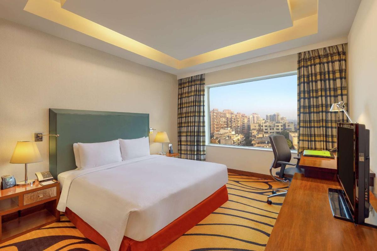 a hotel room with a bed and a large window at DoubleTree by Hilton Gurgaon New Delhi NCR in Gurgaon