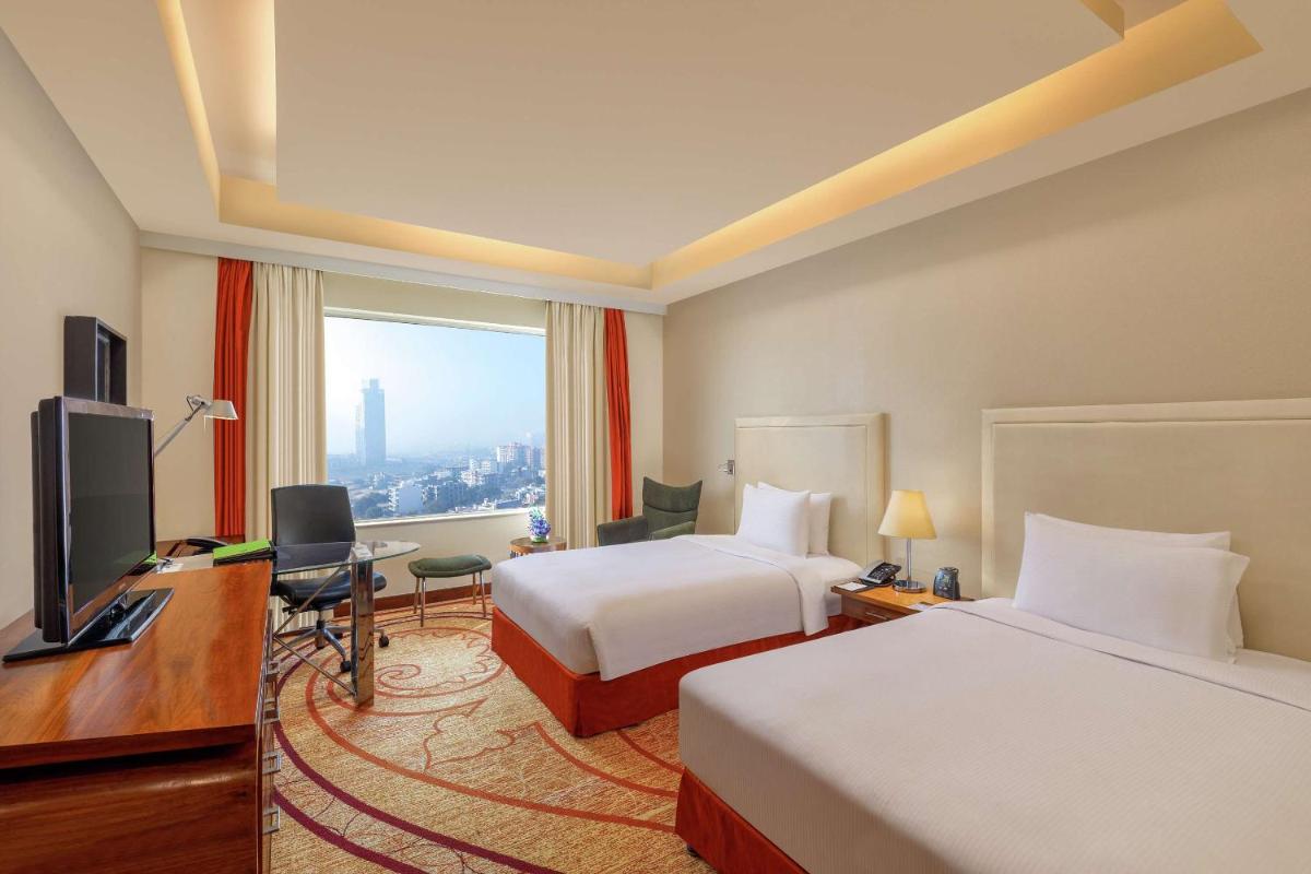 a hotel room with two beds and a desk and a television at DoubleTree by Hilton Gurgaon New Delhi NCR in Gurgaon