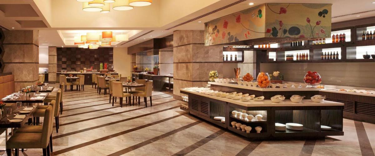 a restaurant with tables and chairs and a buffet at DoubleTree by Hilton Gurgaon New Delhi NCR in Gurgaon