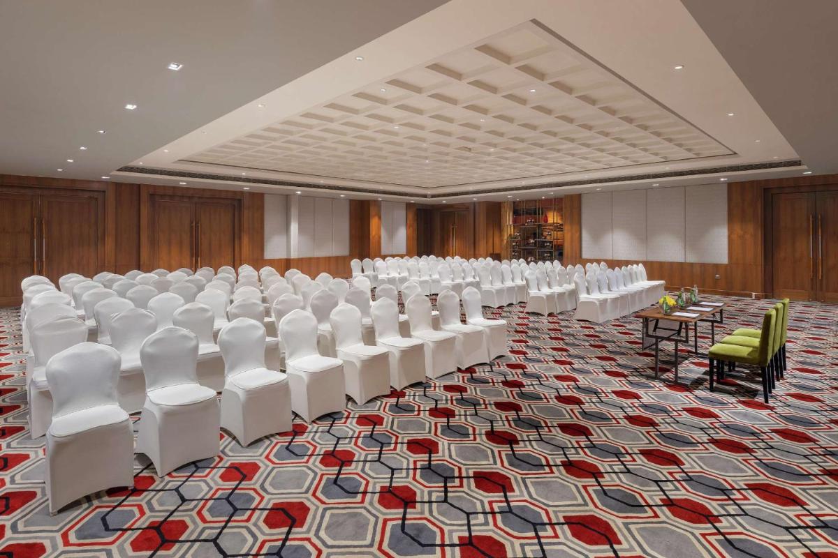a room with rows of white chairs and tables at DoubleTree by Hilton Gurgaon New Delhi NCR in Gurgaon