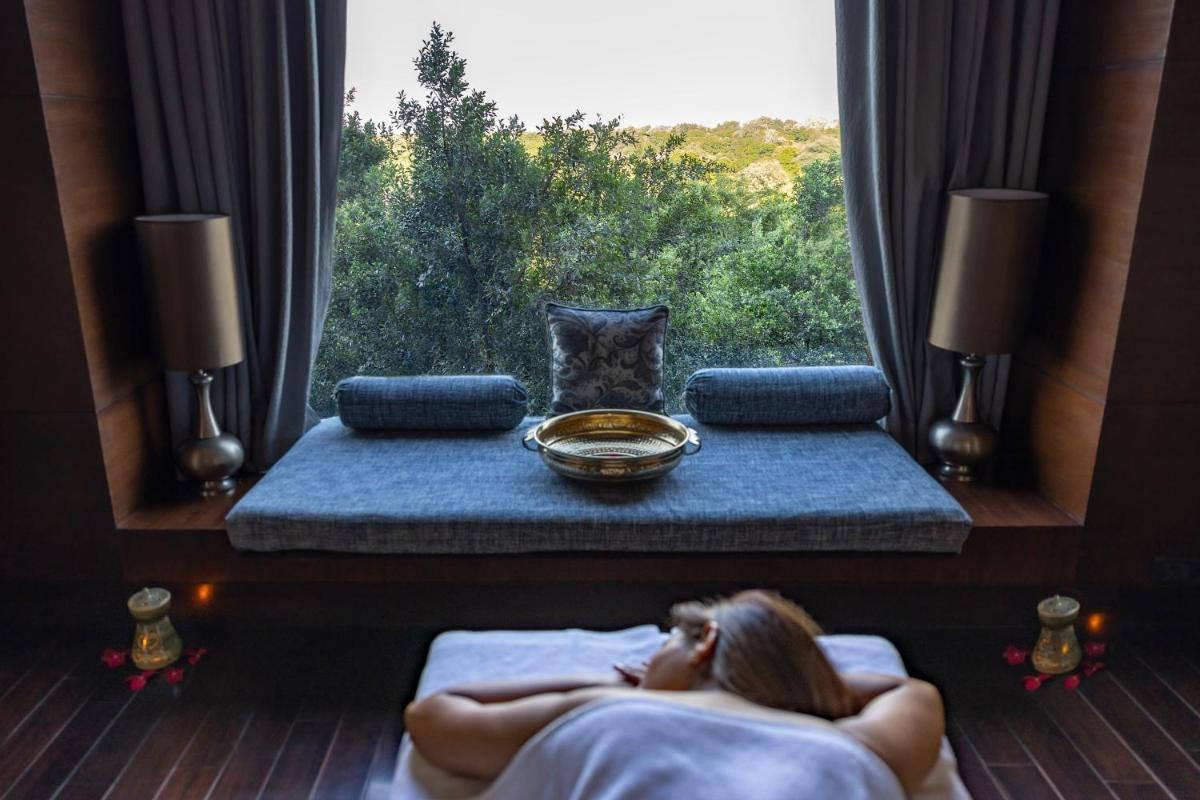 a woman laying in bed in front of a window at The Leela Ambience Gurugram Hotel & Residences - The Luxury Urban Sanctuary in Gurgaon