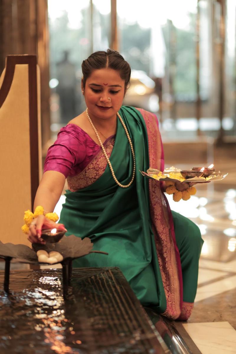 a woman sitting in a chair holding a plate of food at The Leela Ambience Gurugram Hotel & Residences - The Luxury Urban Sanctuary in Gurgaon