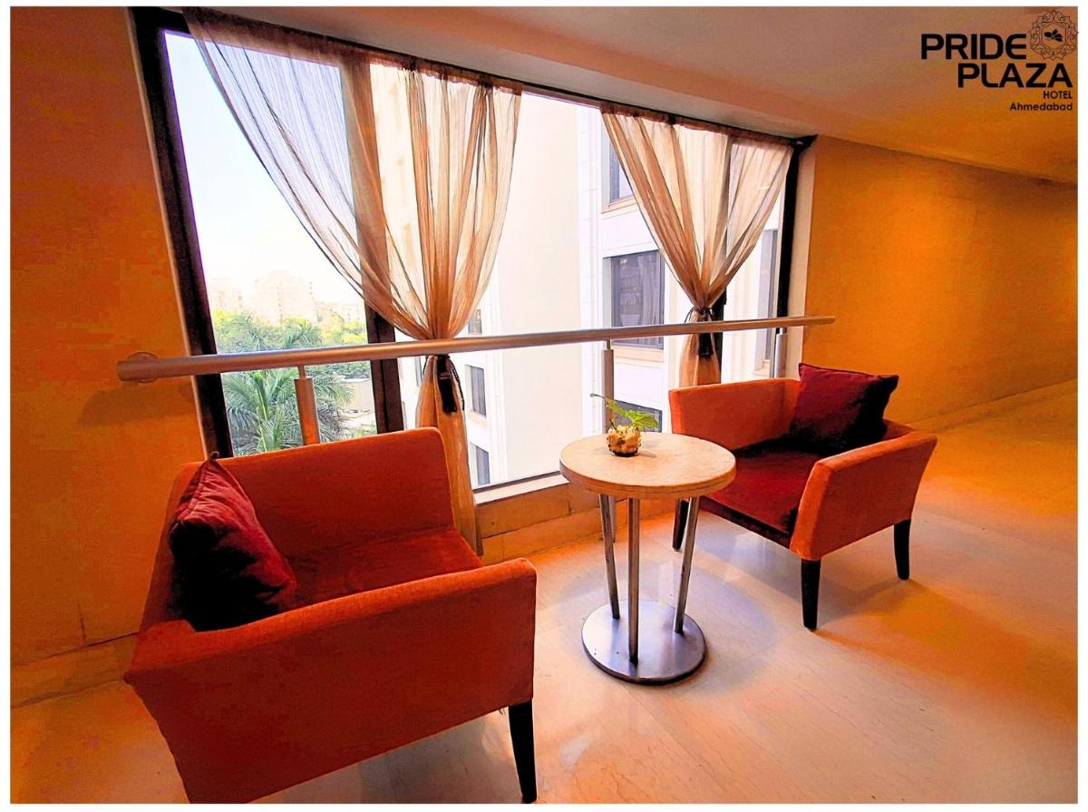 a room with two chairs and a table in front of a window at Pride Plaza Hotel, Ahmedabad in Ahmedabad