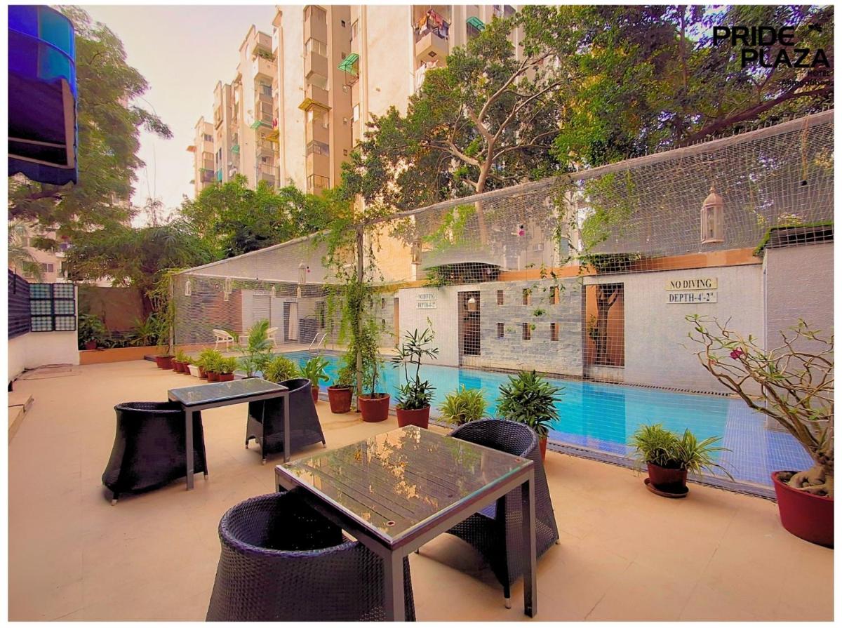 a patio with tables and potted plants and a pool at Pride Plaza Hotel, Ahmedabad in Ahmedabad
