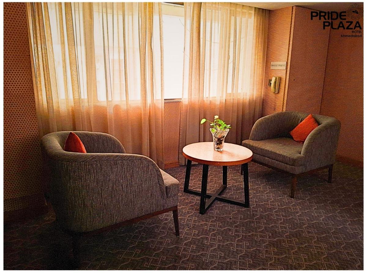 a room with two chairs and a table and a window at Pride Plaza Hotel, Ahmedabad in Ahmedabad